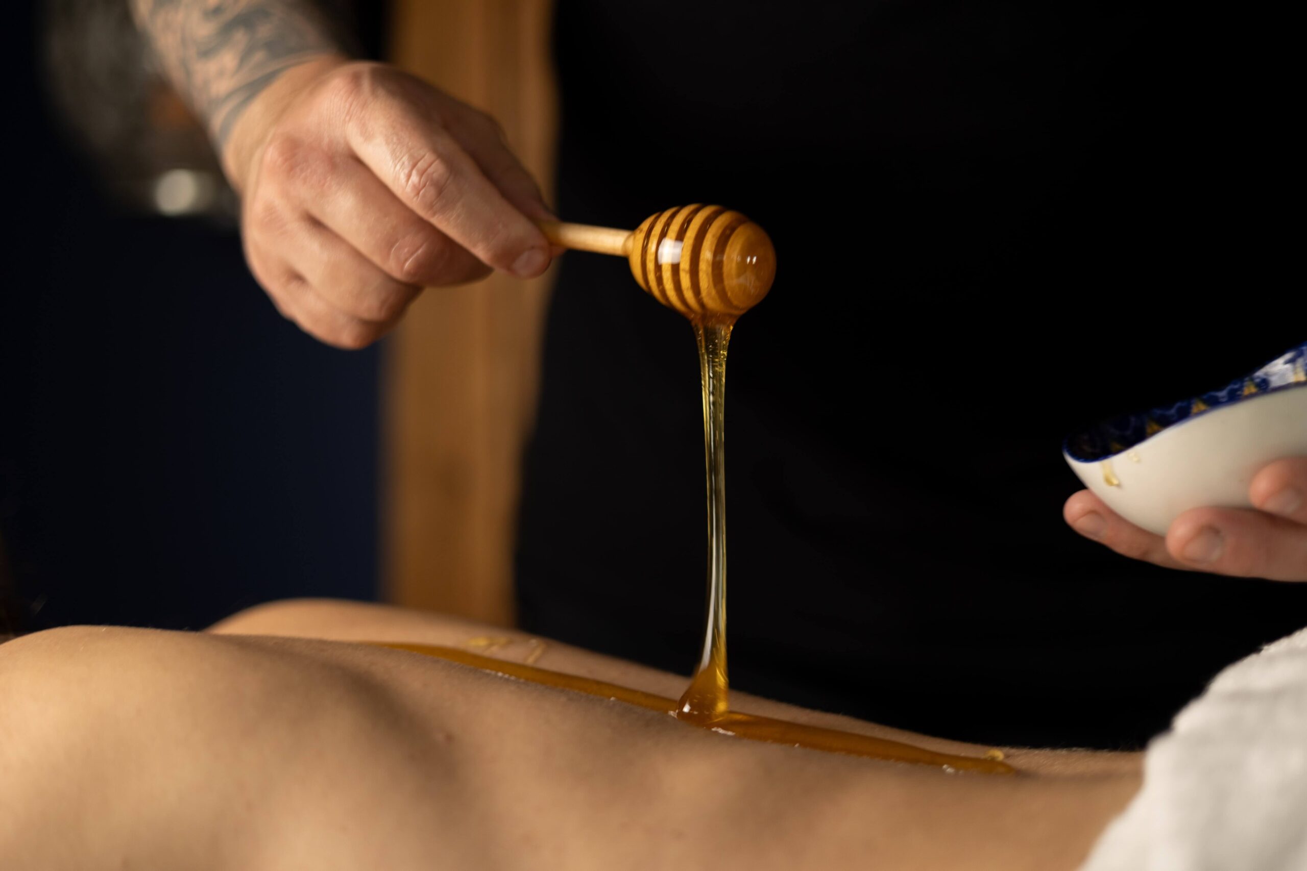 Zdjęcie ukazuje masażystę wykonującego rosyjski masaż miodem w gabinecie Oriental SPA w Jeleniej Górze. Masażysta aplikuje naturalny miód na skórę pacjenta i stosuje techniki masażu, aby poprawić krążenie, detoksykację i elastyczność skóry.